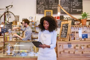 Business woman dressed in an apron looking down at business tablet device