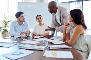 Collegues at a table discussing work surrounded by paper and work