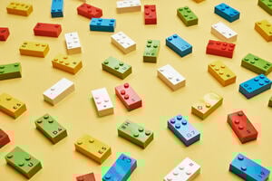 A selection of different LEGO Braille Bricks on a yellow table