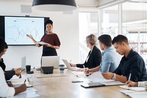 Board room presentation with charts on a screen